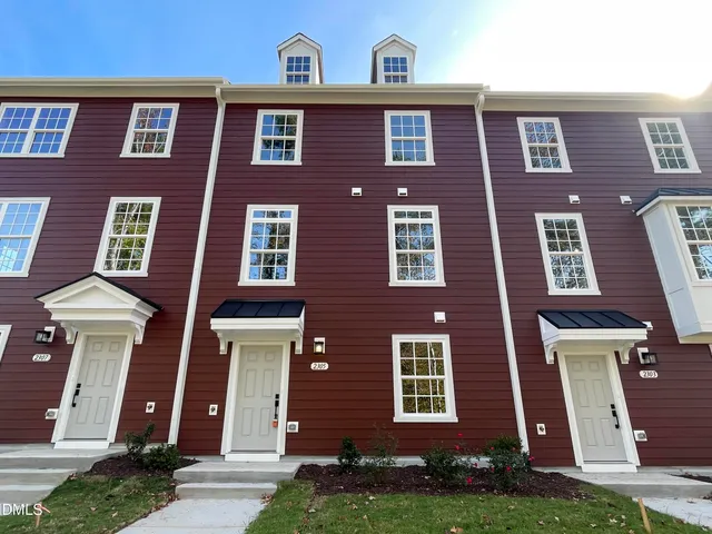 front view of a brick house with a yard and many windows