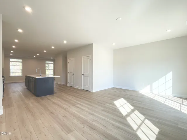a view of an empty room with wooden floor and windows