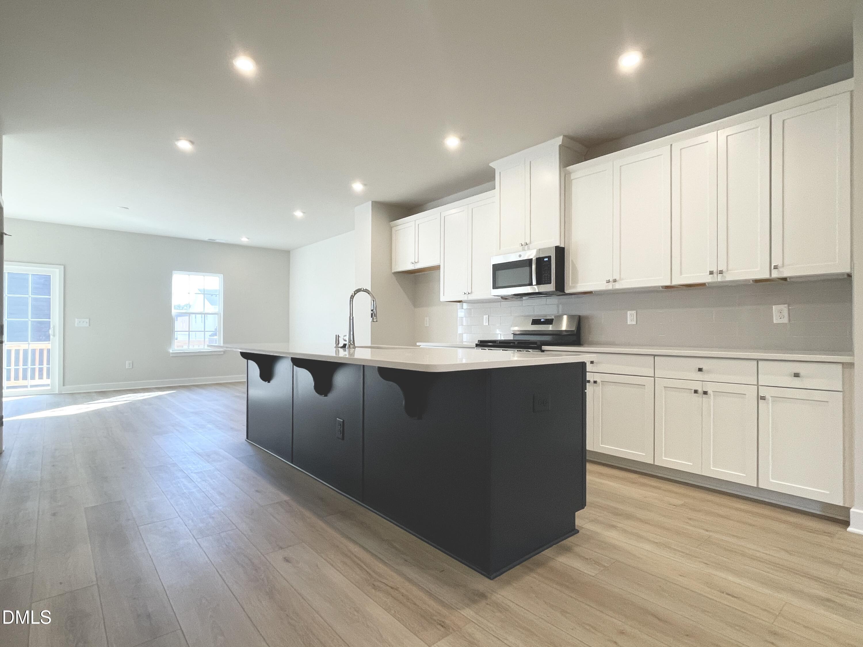 2305 Pitchfork Lane Durham, NC 27713 - Photo 7 of 27 a kitchen with kitchen island granite countertop a sink dishwasher a refrigerator and white cabinets with wooden floor