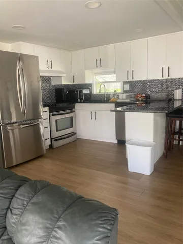 a kitchen with granite countertop a refrigerator stove top oven and sink