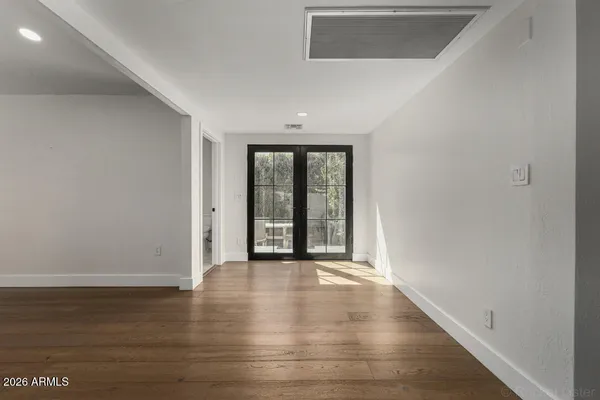 a view of an empty room with wooden floor and a window