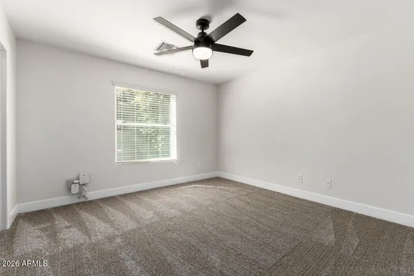an empty room with ceiling fan and windows