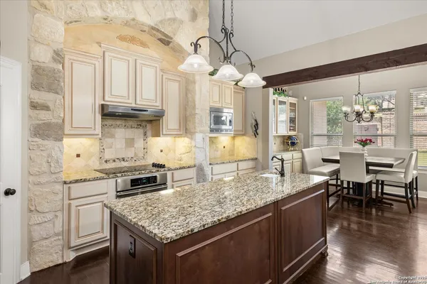 a kitchen with kitchen island granite countertop a table chairs stove and cabinets