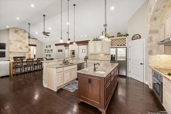 a kitchen with stainless steel appliances granite countertop a stove a sink dishwasher and a refrigerator with wooden floor