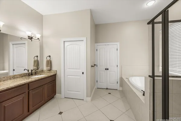 a spacious bathroom with a granite countertop sink a mirror and a bathtub