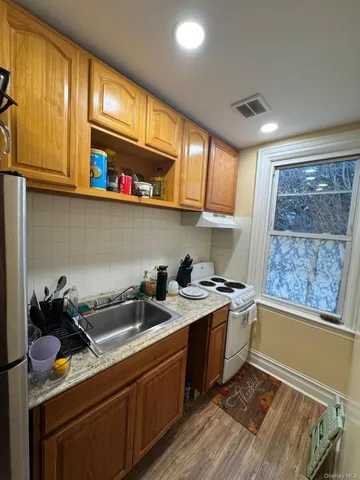 a kitchen with a sink a stove cabinets and a wooden floor