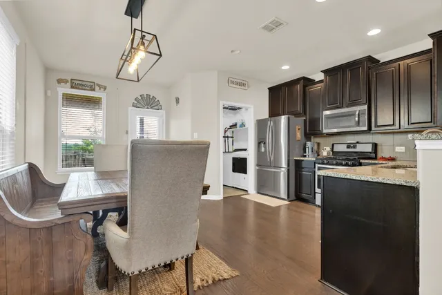 a kitchen with stainless steel appliances granite countertop a refrigerator a stove and a dining table with wooden floor