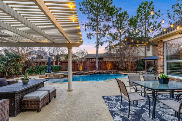 a view of a patio with dining table and chairs with plants and wooden fence