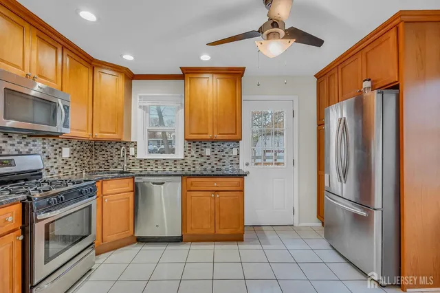 a kitchen with stainless steel appliances granite countertop a refrigerator a stove and a sink with cabinets