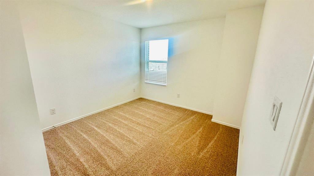 192 Rodney Boat Road Kyle, TX 78640 - Photo 24 of 38 A well-lit bedroom features plush carpeting and a window with blinds, ready for personalization.