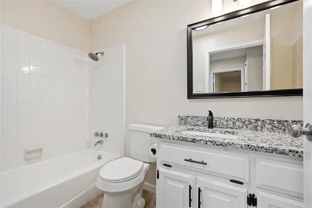 a bathroom with a granite countertop toilet sink and mirror