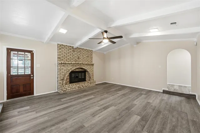 an empty room with windows fireplace and a kitchen view
