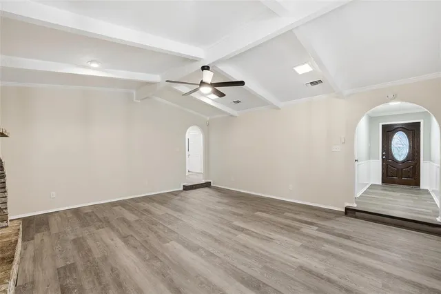 an empty room with wooden floor a ceiling fan and windows