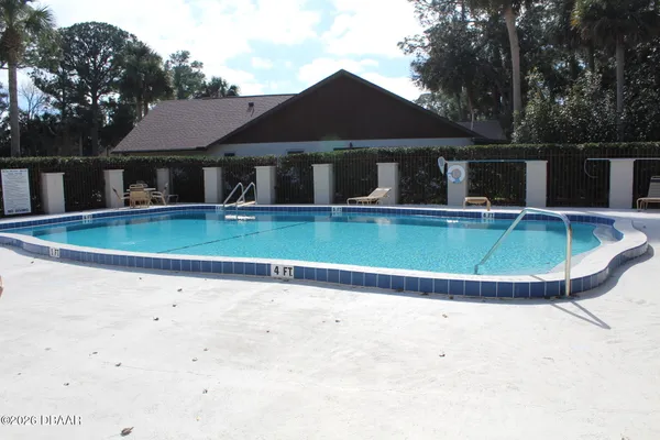 a view of a house with swimming pool and trees in the background