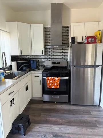 a kitchen with stainless steel appliances white cabinets and wooden floor