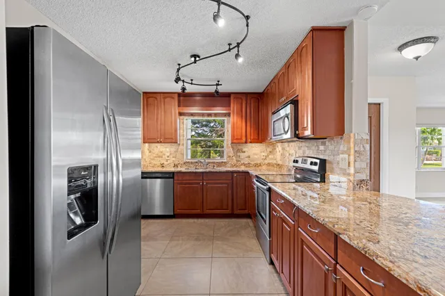 a kitchen with stainless steel appliances granite countertop a refrigerator a sink a stove and dishwasher