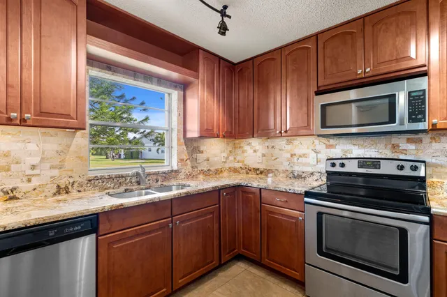 a kitchen with granite countertop cabinets stainless steel appliances and a sink