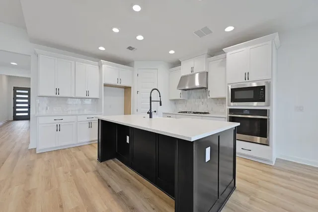 a hall with kitchen island a sink and wooden floor