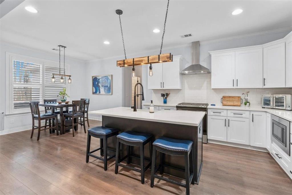 7705 Wandering Oak Way Cumming, GA 30041 - Photo 22 of 57 a kitchen with kitchen island a dining table and chairs