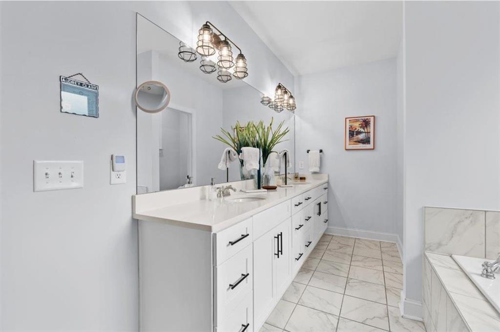 7705 Wandering Oak Way Cumming, GA 30041 - Photo 28 of 57 a bathroom with a sink a mirror and a shower
