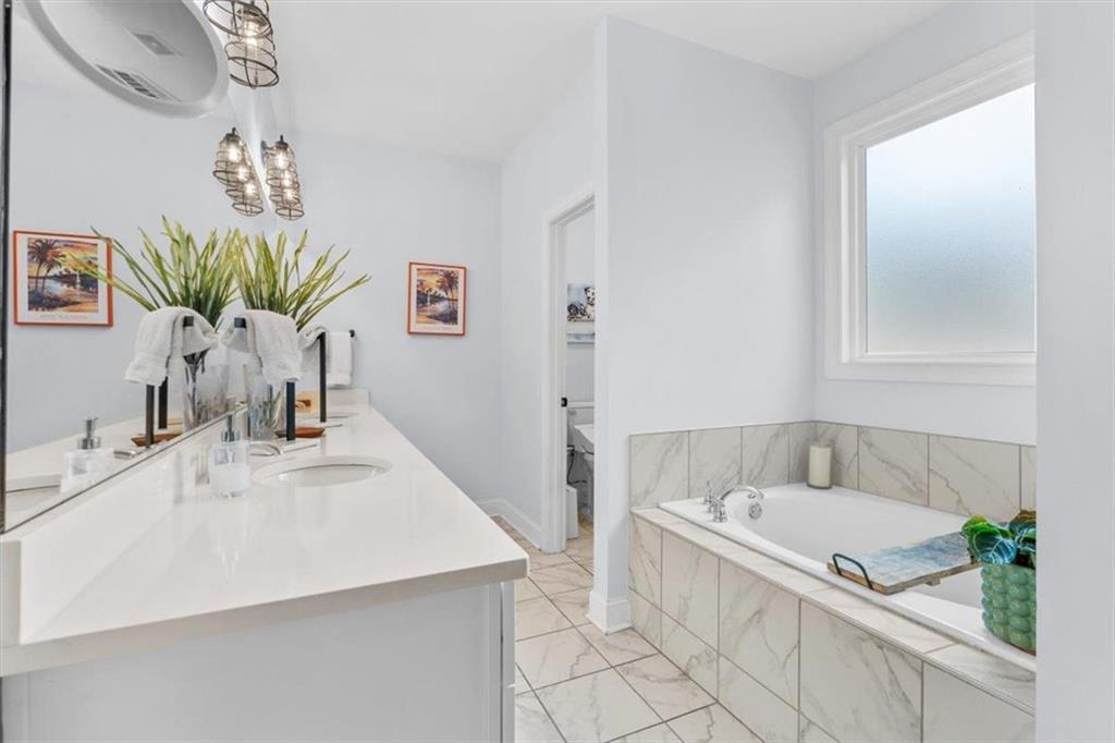7705 Wandering Oak Way Cumming, GA 30041 - Photo 29 of 57 a bathroom with a granite countertop sink a mirror and a bathtub