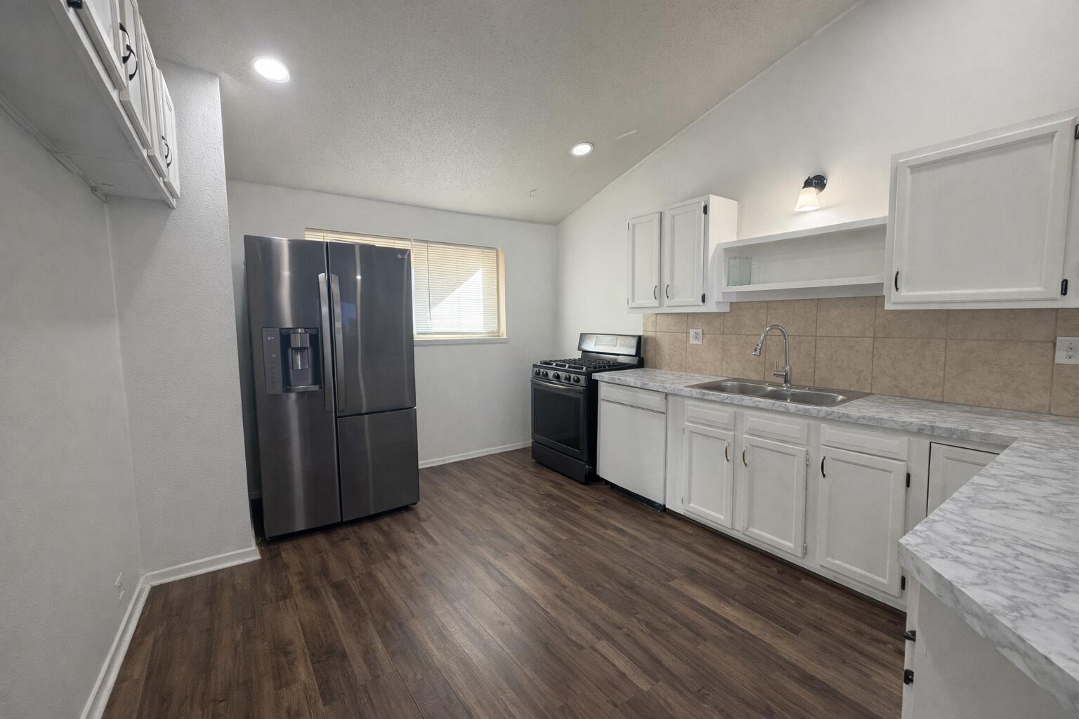 5308 48th Street Lubbock, TX 79414 - Photo 3 of 12 a kitchen with a sink a refrigerator and cabinets