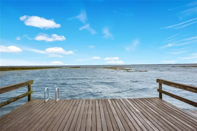 a view of deck and lake with houses in the back