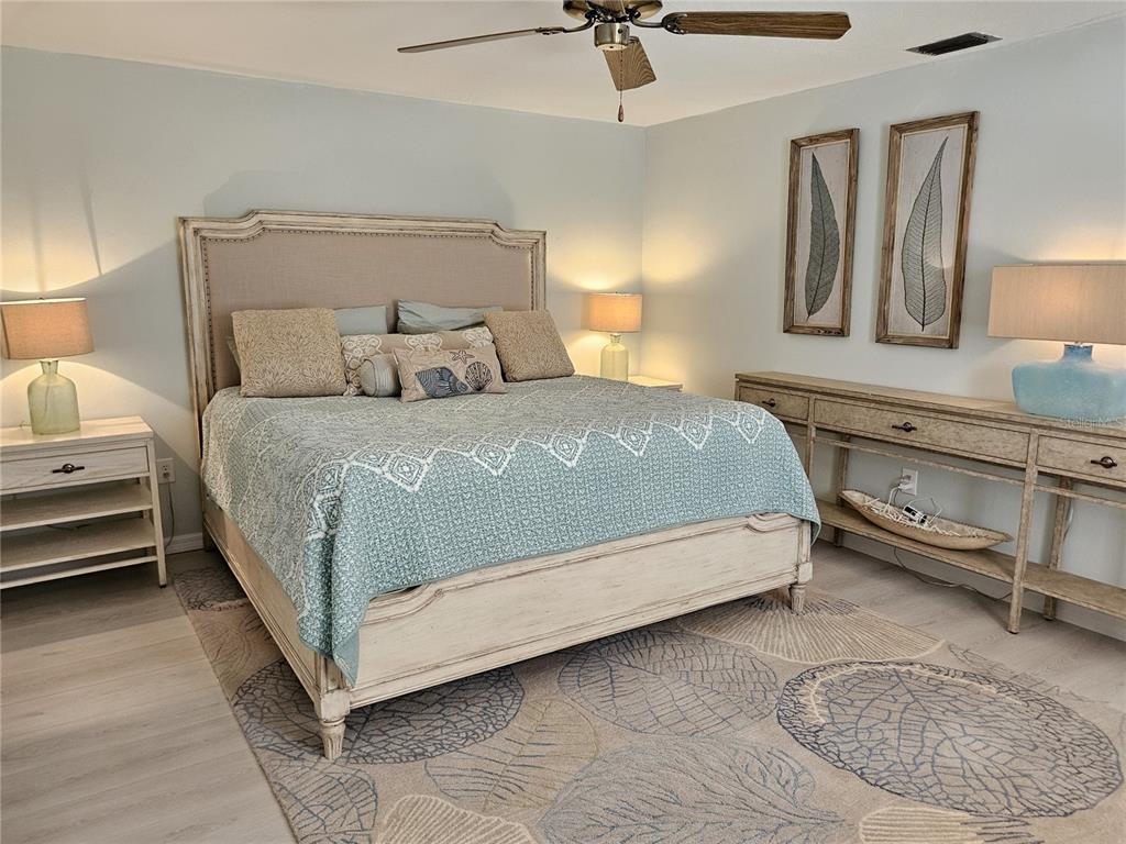 744 Cadiz Road, Unit 1 Venice, FL 34285 - Photo 29 of 46 a bed sitting in a bedroom next to a lamp and a chandelier