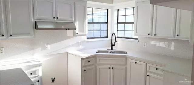 a kitchen with stainless steel appliances granite countertop white cabinets and window