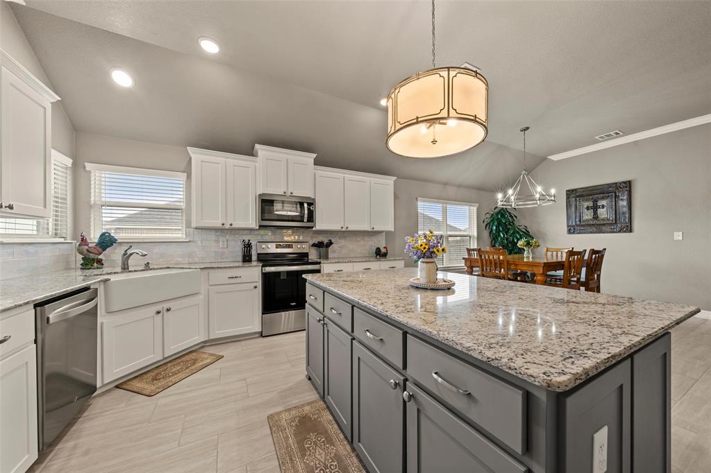 828 Agile Street Hewitt, TX 76643 - Photo 14 of 30 a kitchen with granite countertop stainless steel appliances a sink dishwasher a microwave oven and a dining table with wooden floor