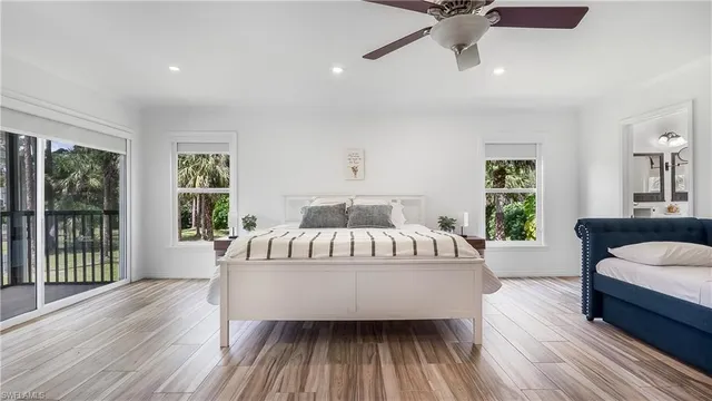 a spacious bedroom with a large bed a chandelier and windows