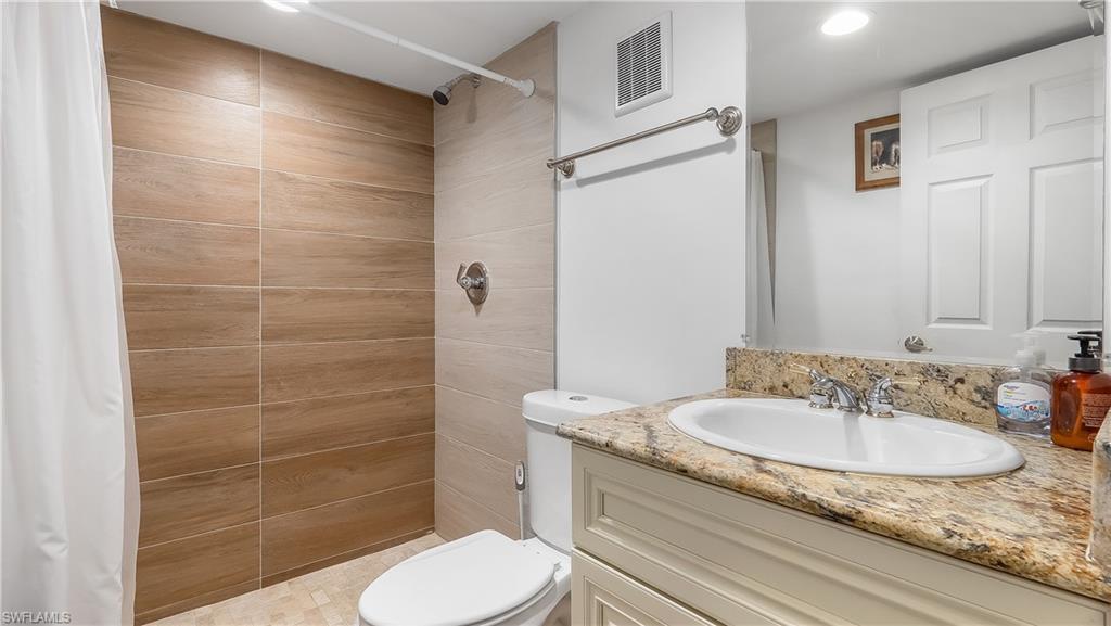 2920 24th Avenue Southeast Naples, FL 34117 - Photo 25 of 50 a bathroom with a granite countertop sink a toilet a mirror and shower