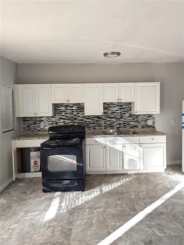 a kitchen with granite countertop a stove sink and cabinets