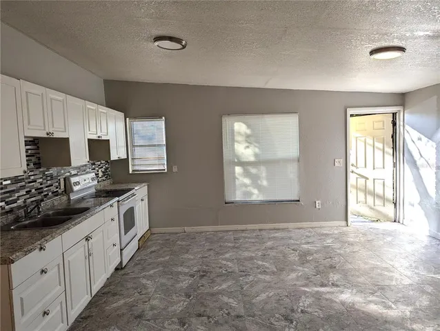 a kitchen with granite countertop a sink and a stove top oven