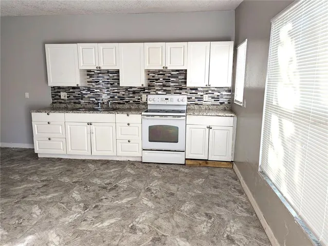 a kitchen with stainless steel appliances granite countertop a stove a sink and a white cabinets