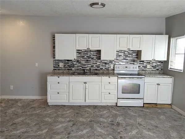 a kitchen with granite countertop white cabinets and white stainless steel appliances