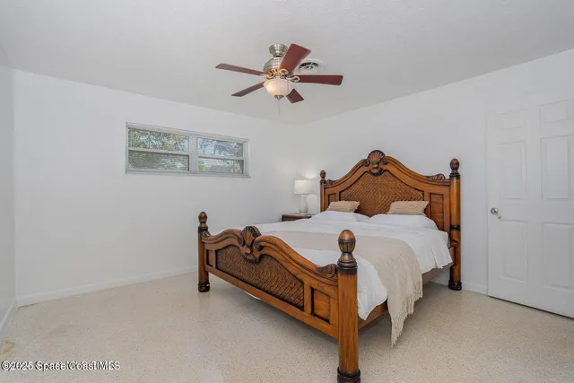 a bedroom with a bed and a chandelier fan