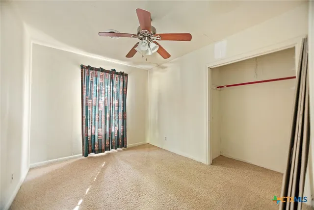 a view of a room with a ceiling fan and a window