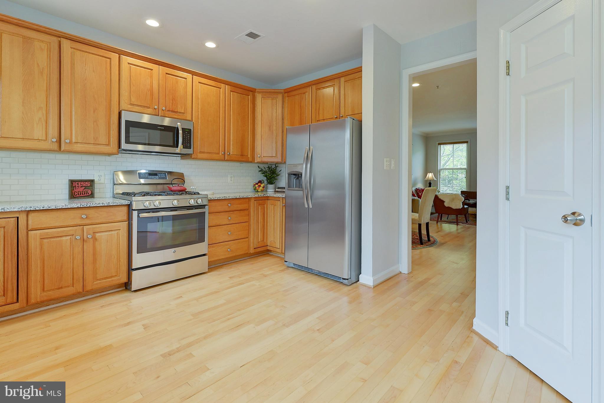 807 Capitol Square Place Southwest Washington, DC 20024 - Photo 12 of 30 a kitchen with stainless steel appliances granite countertop a stove top oven a refrigerator and white cabinets with wooden floors
