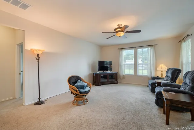 a living room with furniture a ceiling fan a flat screen tv and a window
