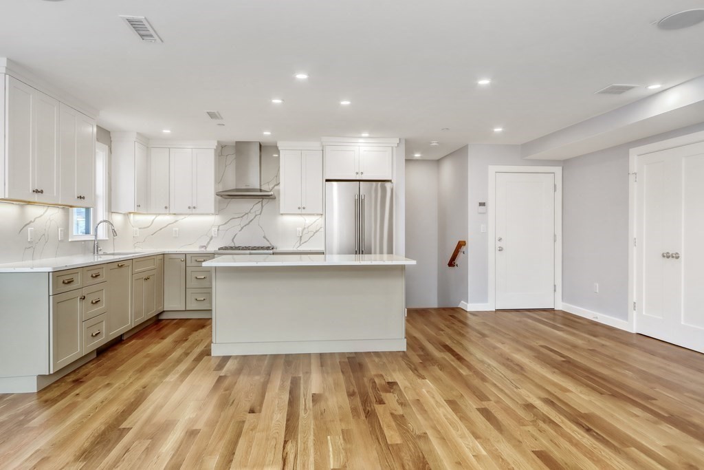 a kitchen with kitchen island a sink dishwasher a stove and white cabinets with wooden floor