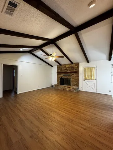 a view of empty room with wooden floor and fireplace