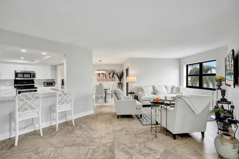 a kitchen with stainless steel appliances granite countertop a stove top oven a sink dishwasher a refrigerator and a dining table with wooden floor