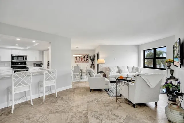 a kitchen with stainless steel appliances granite countertop a stove top oven a sink dishwasher a refrigerator and a dining table with wooden floor