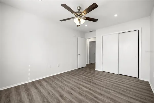 an empty room with wooden floor and ceiling fan