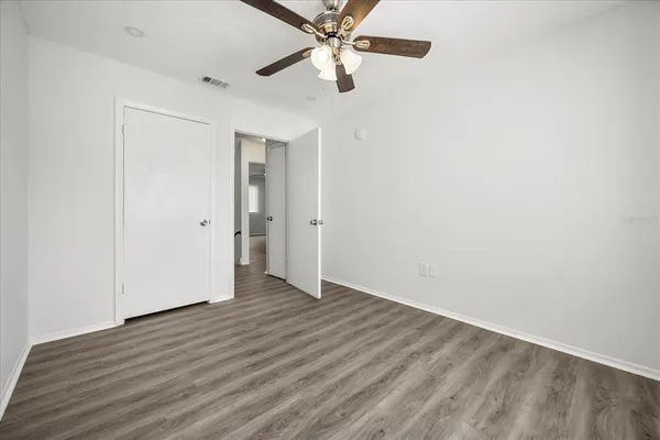 an empty room with wooden floor a ceiling fan and closet