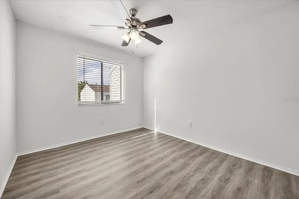 an empty room with wooden floor fan and windows