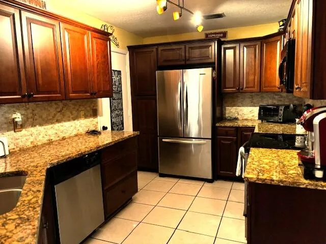 a kitchen with stainless steel appliances granite countertop a refrigerator a stove a sink and dishwasher