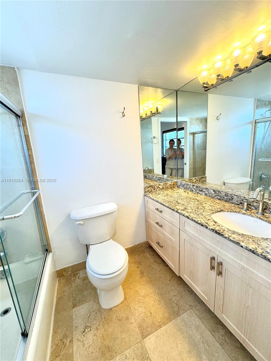 1020 94th Street, Unit 402 Bay Harbor Islands, FL 33154 - Photo 12 of 15 a bathroom with a granite countertop sink a large mirror and a toilet