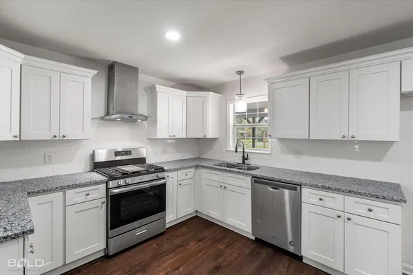 a kitchen with granite countertop white cabinets and white stainless steel appliances